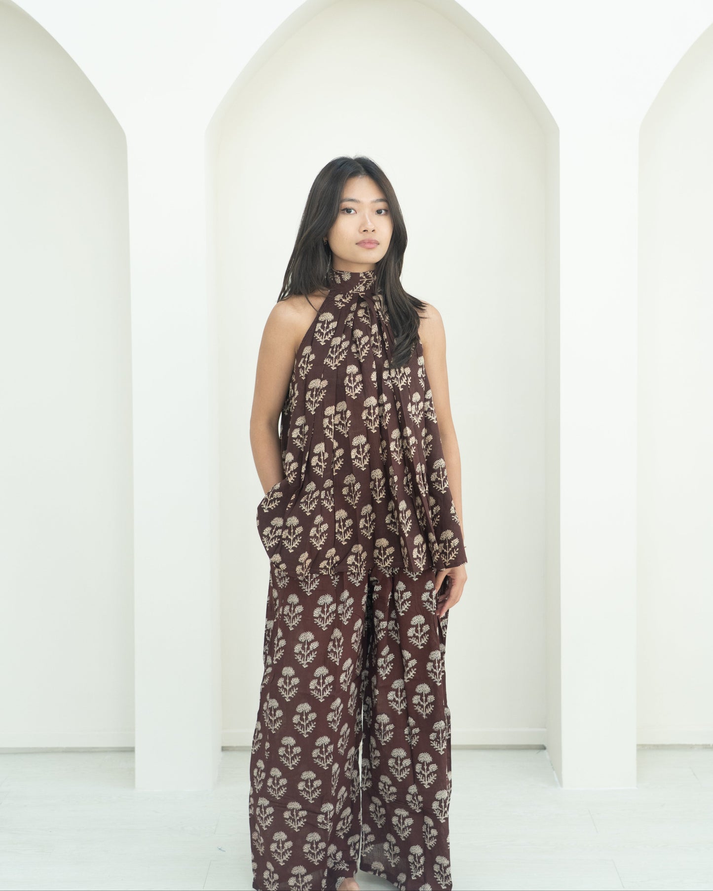 Woman wearing a brown floral outfit standing against a white background