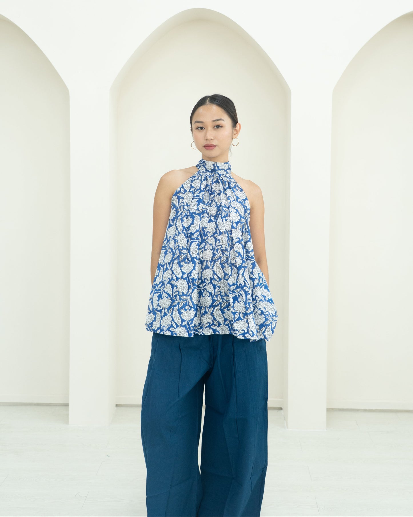 Woman wearing a blue and white floral top with blue pants against a white background