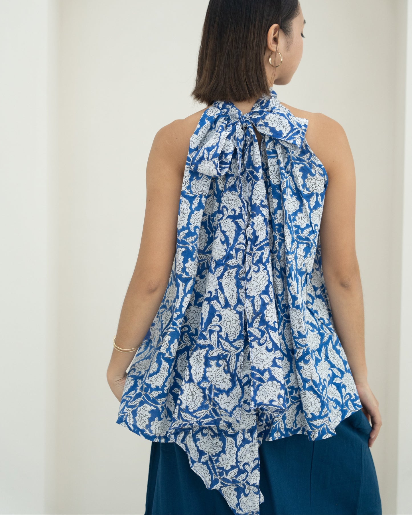 Woman wearing a blue floral sleeveless top against a white background
