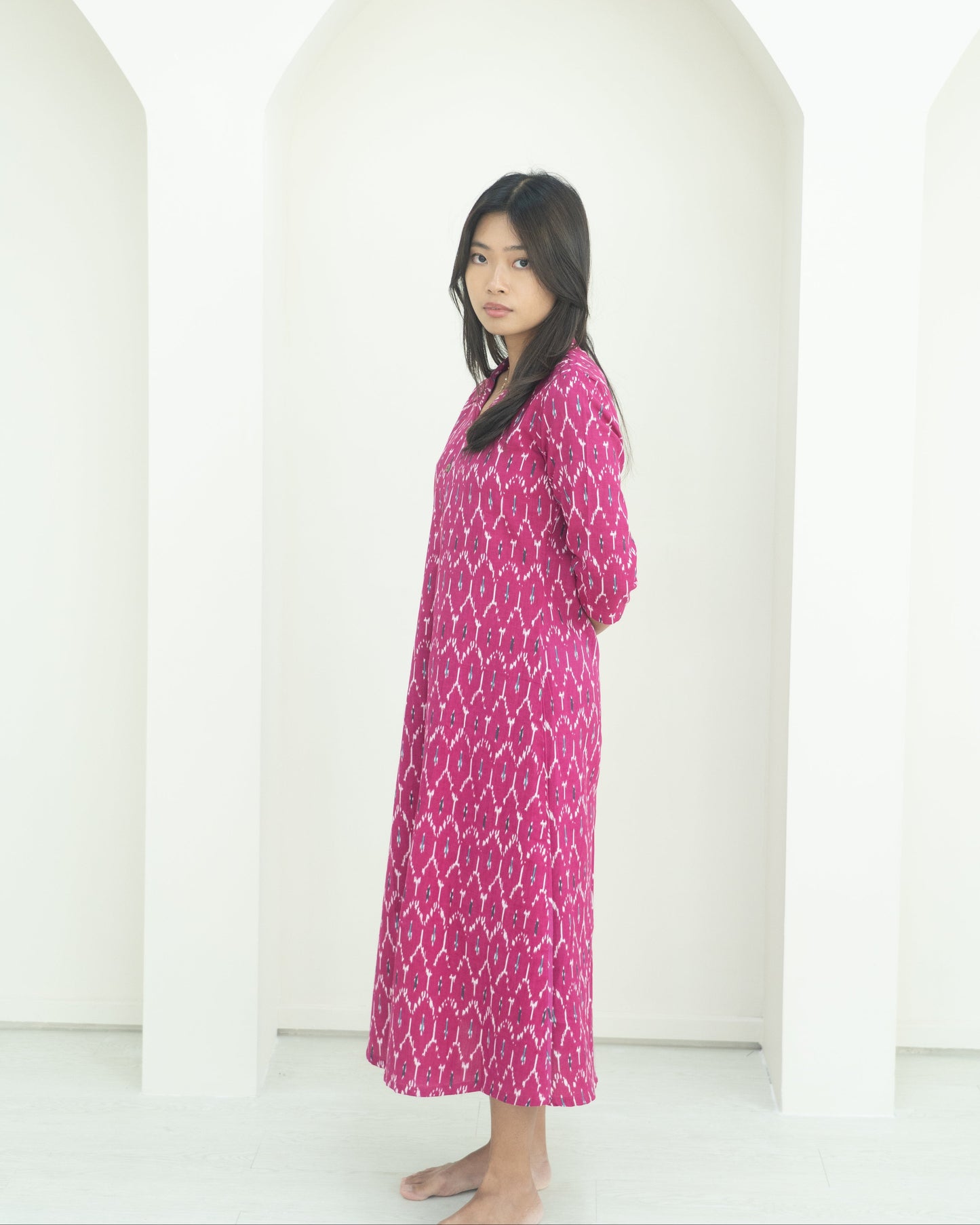 Woman wearing a pink patterned dress standing against a white background