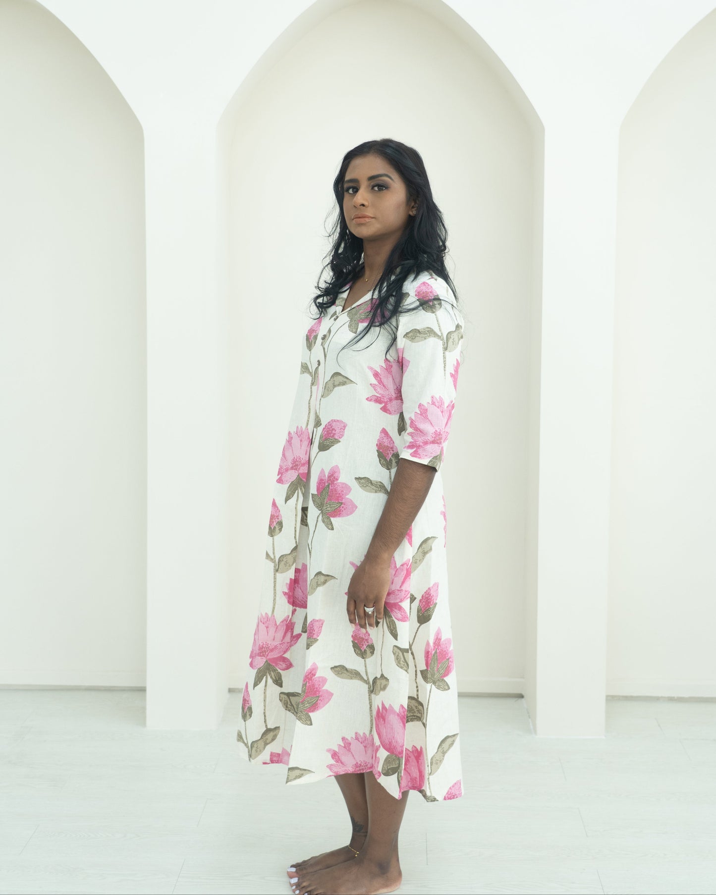 Woman wearing a floral dress standing in front of white arches.