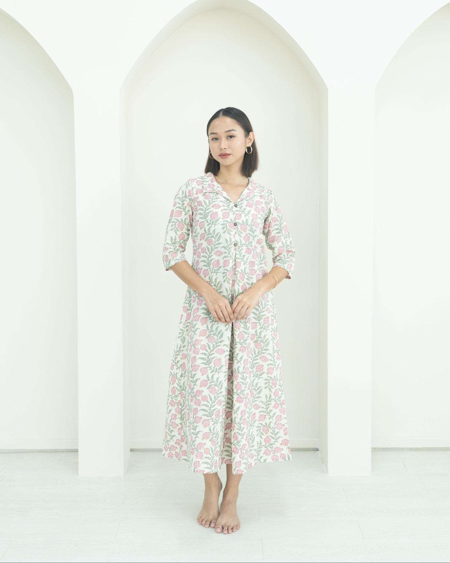 Lady standing against white background in floral dress