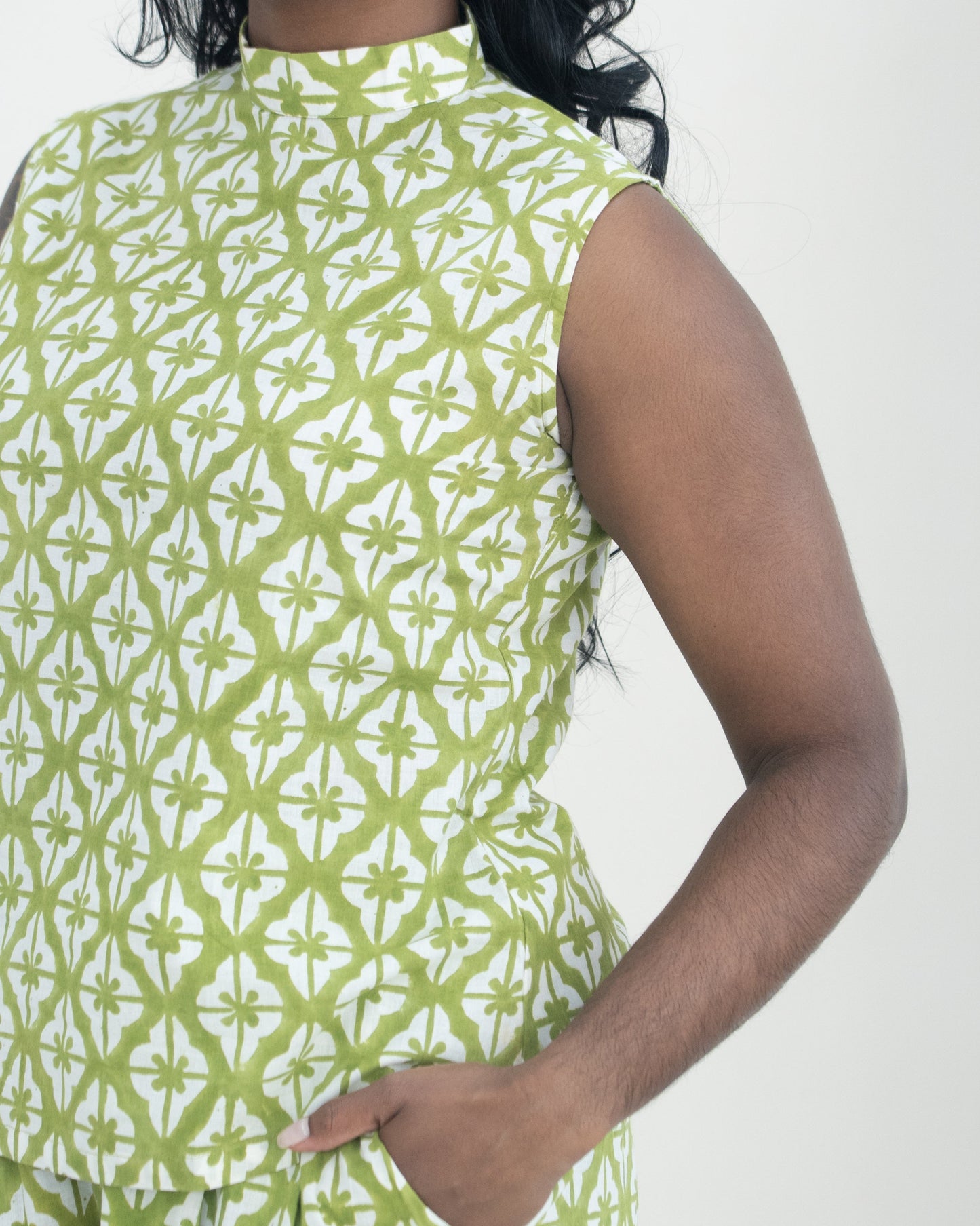 Woman wearing a green and white patterned sleeveless co-ord against a white background