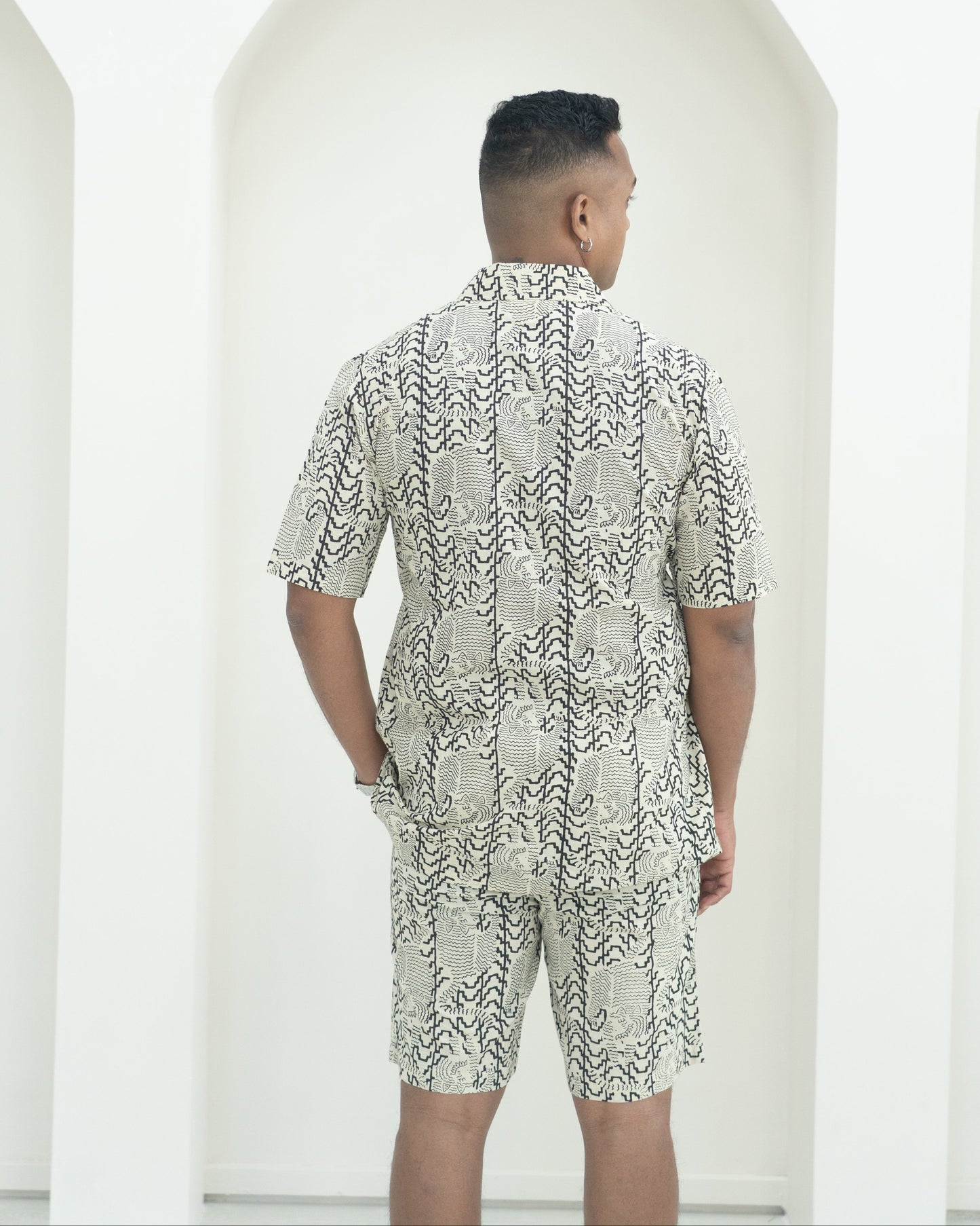 Person wearing a patterned outfit standing in front of white background.