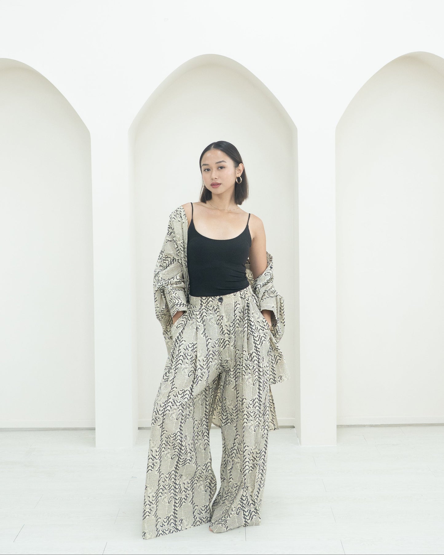 Woman wearing a patterned outfit standing in front of white arches.