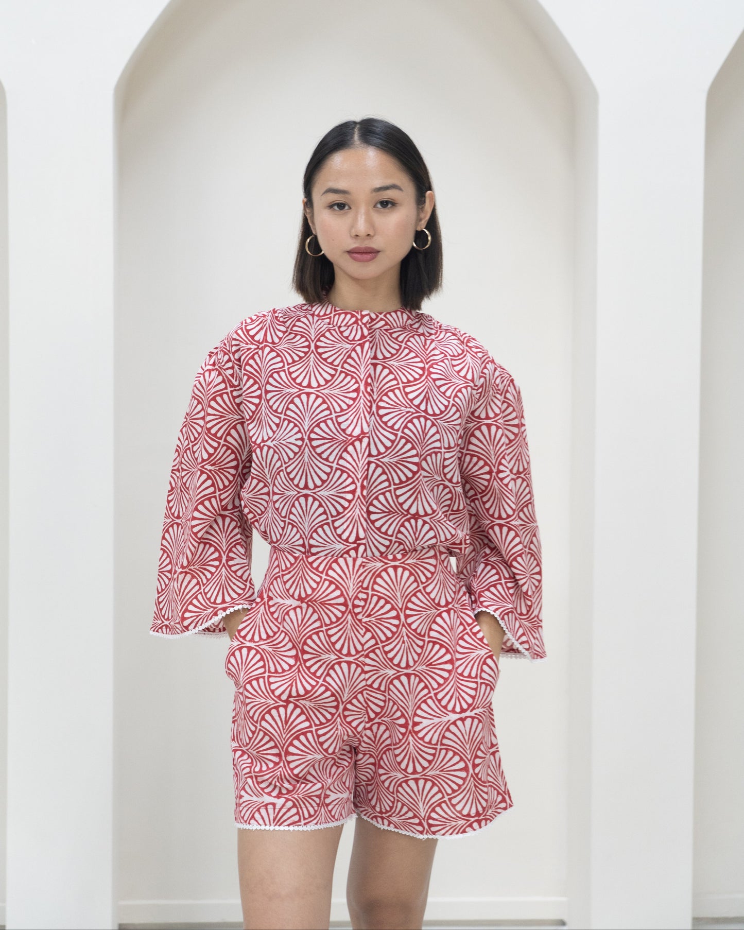 Woman wearing a red and white patterned outfit standing against a white background