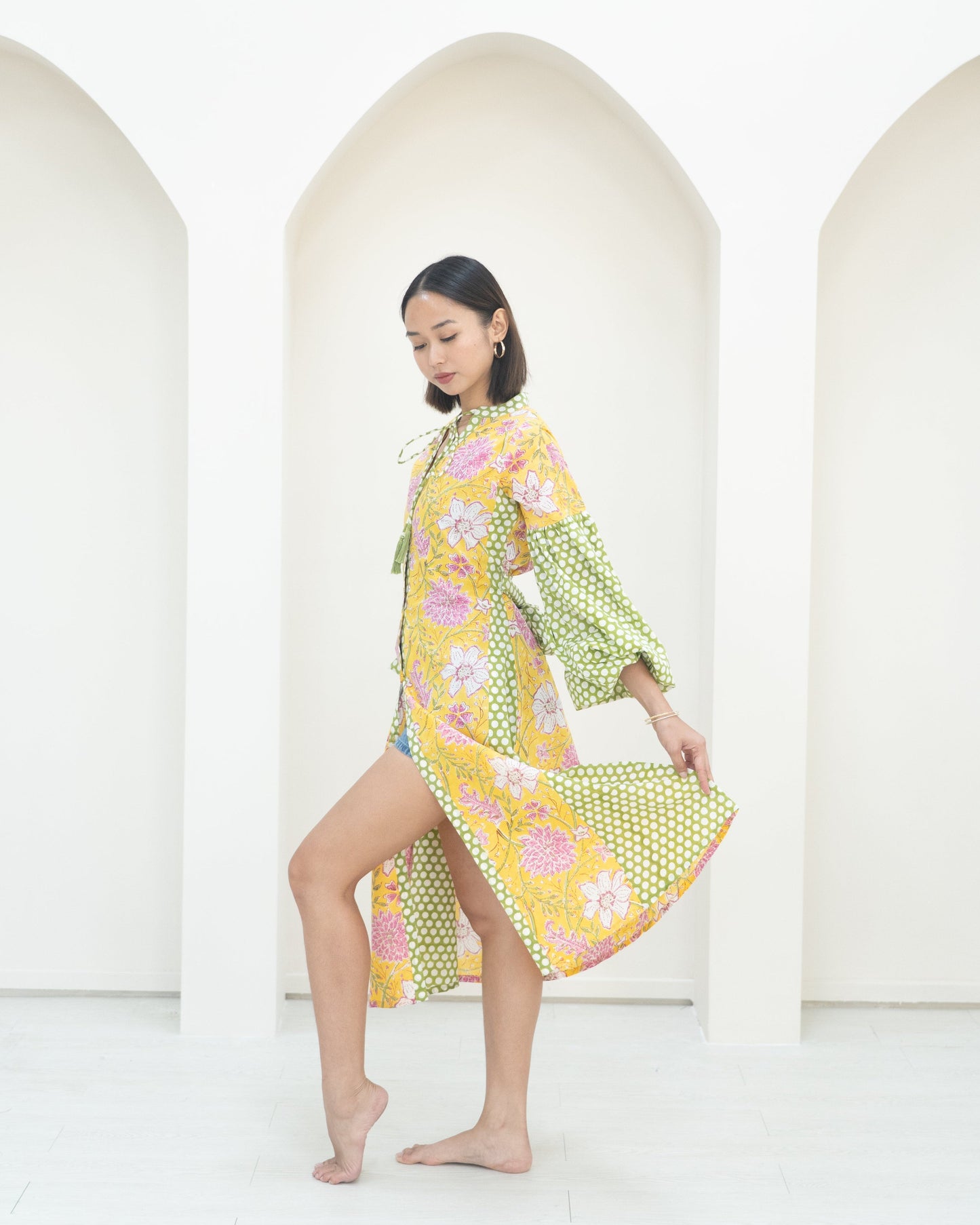 Woman wearing a colorful floral dress against a white background