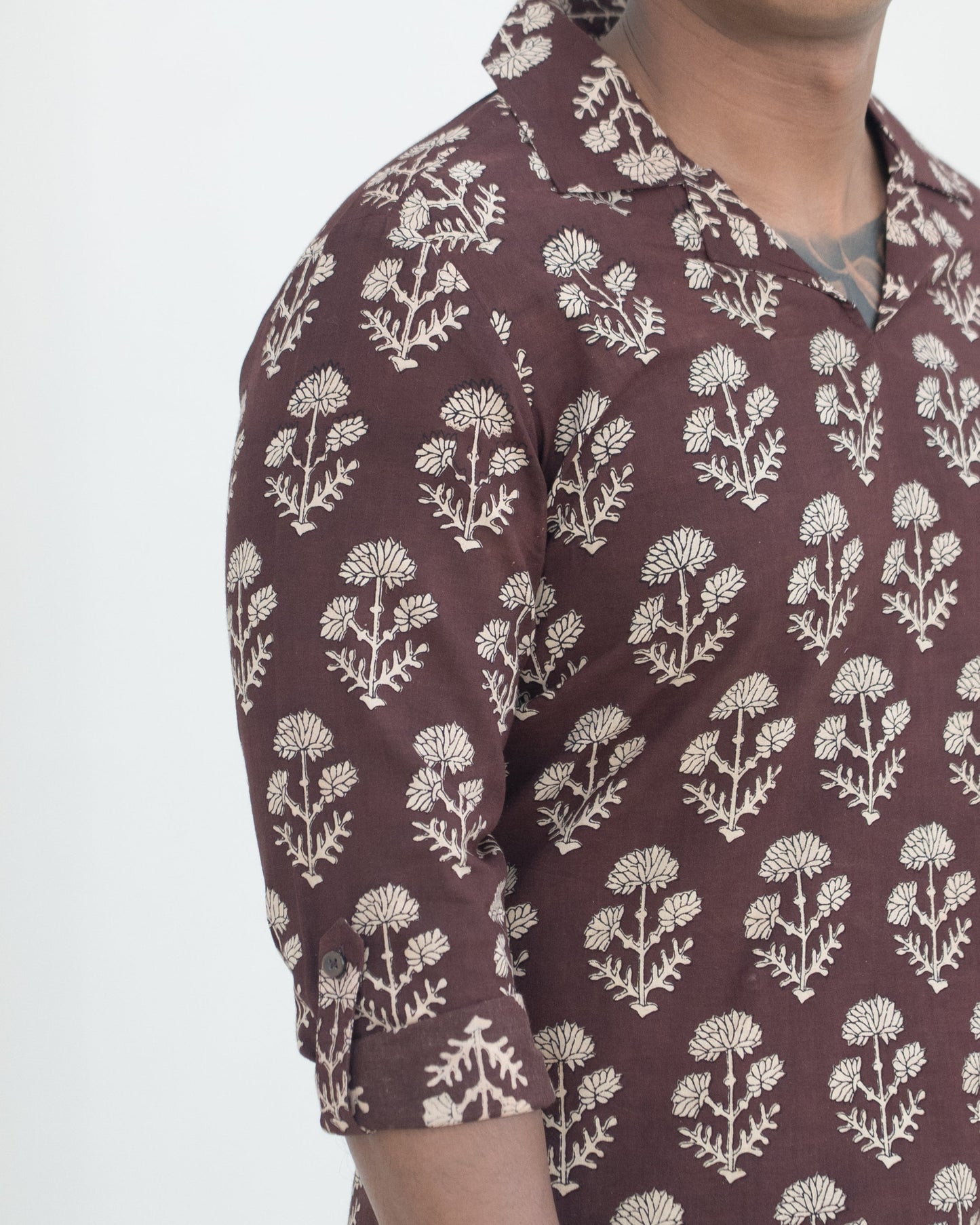 Man wearing a brown floral patterned shirt against a white background