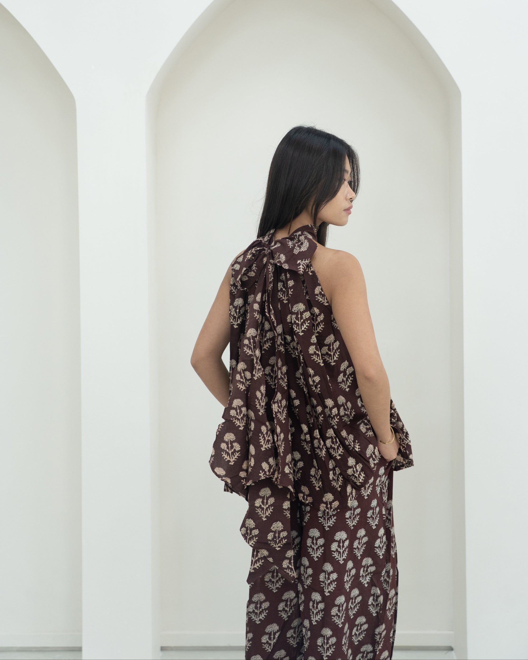 Woman wearing a floral outfit standing against a white background