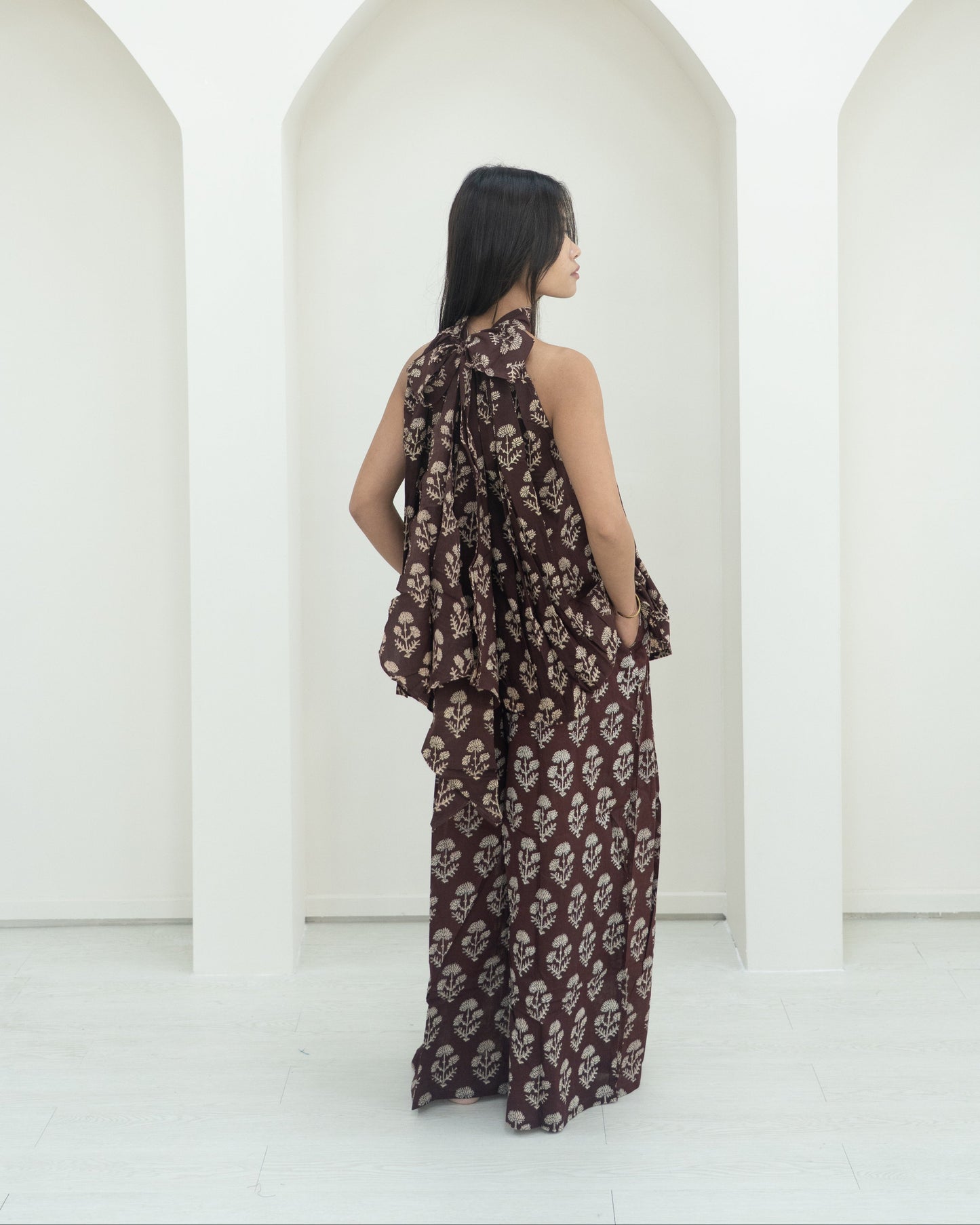 Woman in a floral outfit standing in front of white arches