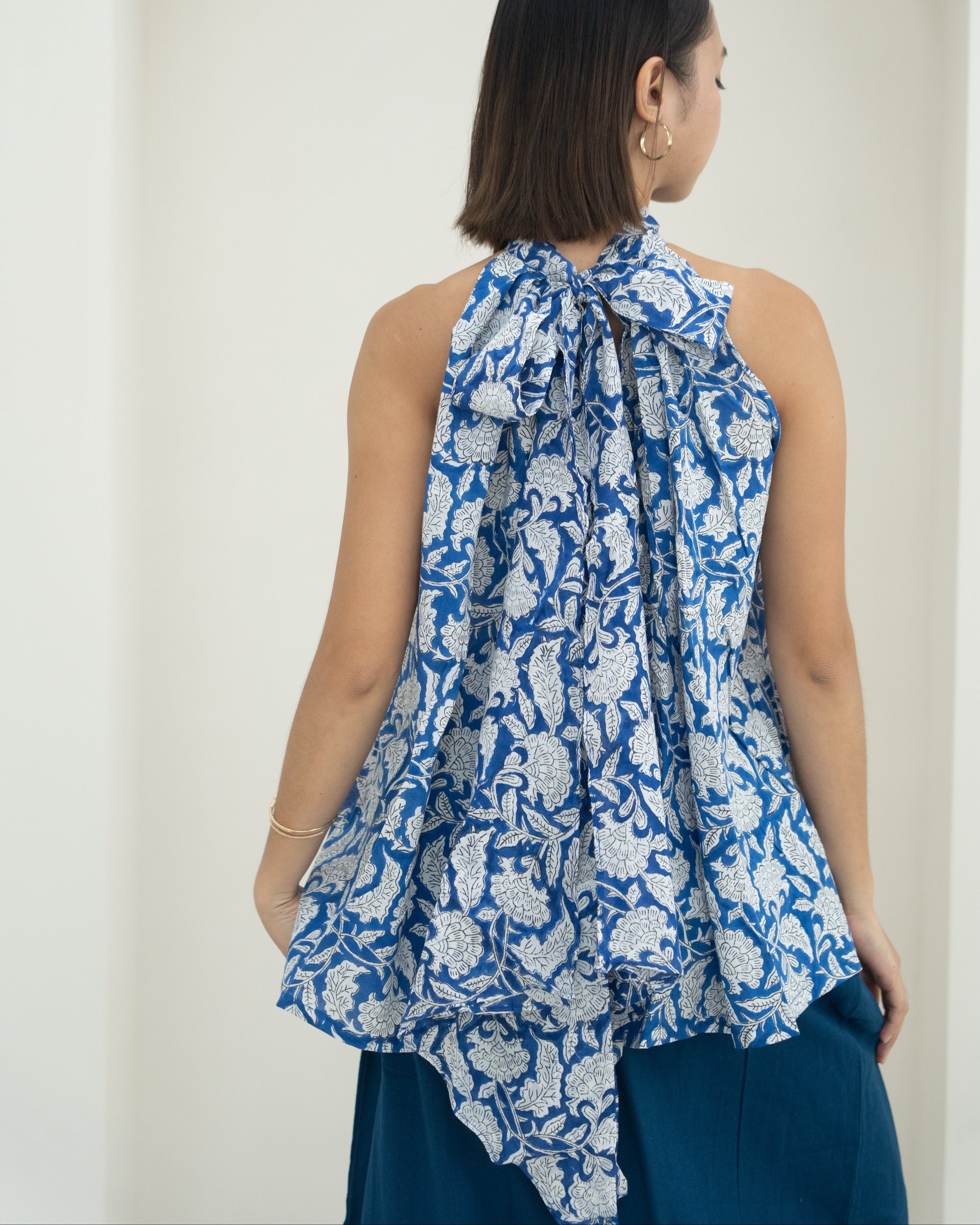 Woman wearing a blue floral sleeveless top against a white background