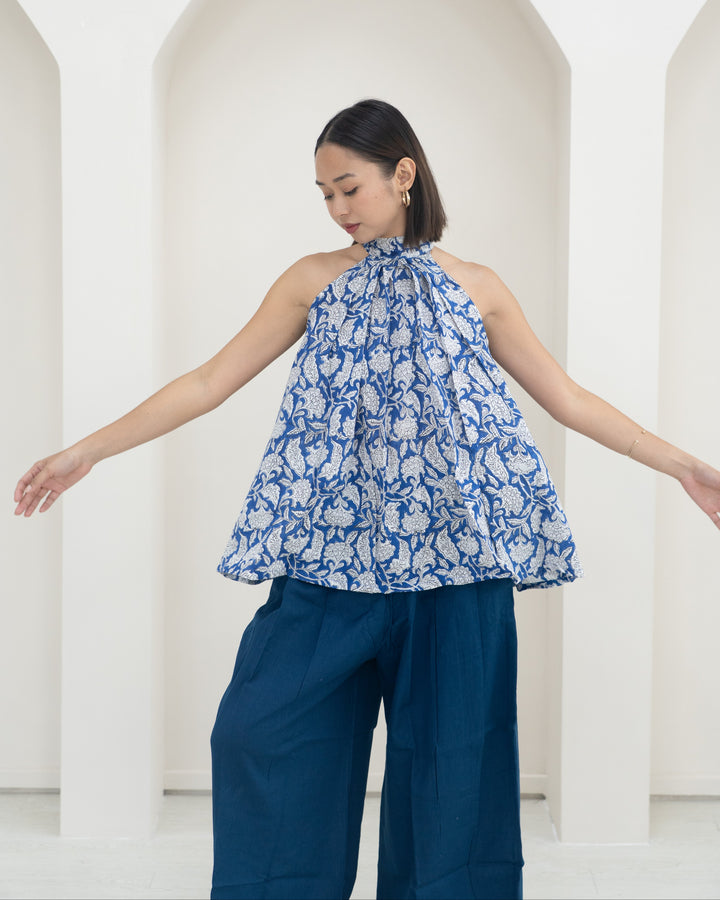 Woman wearing a blue floral top and blue pants against a white background