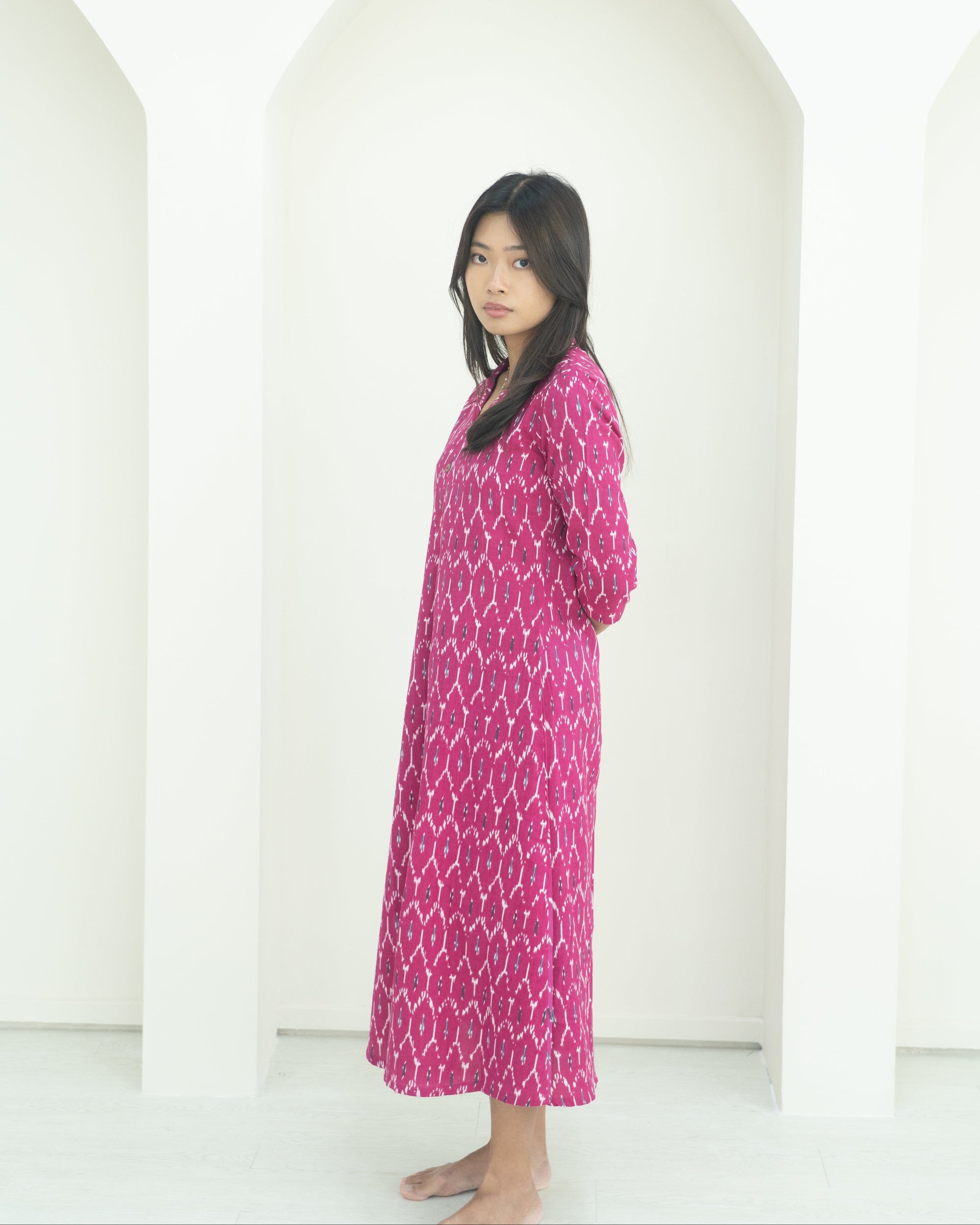 Woman wearing a pink patterned dress standing against a white background