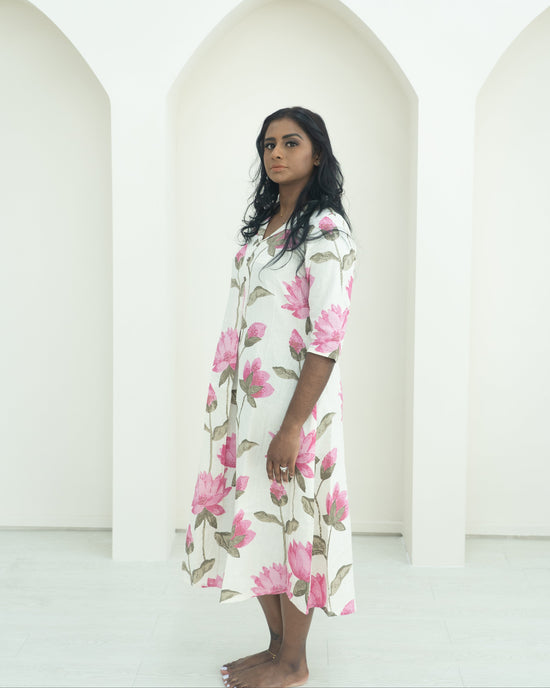 Woman wearing a floral dress standing in front of white arches.