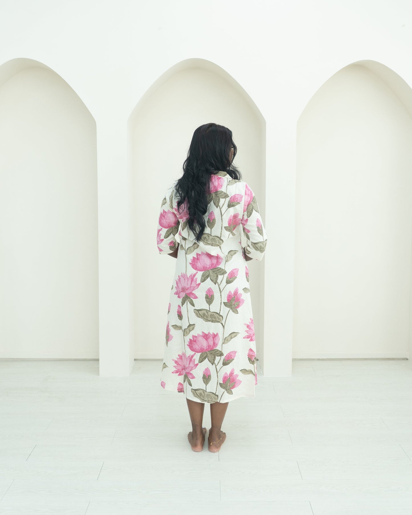 Person wearing a floral dress standing in front of three arches.