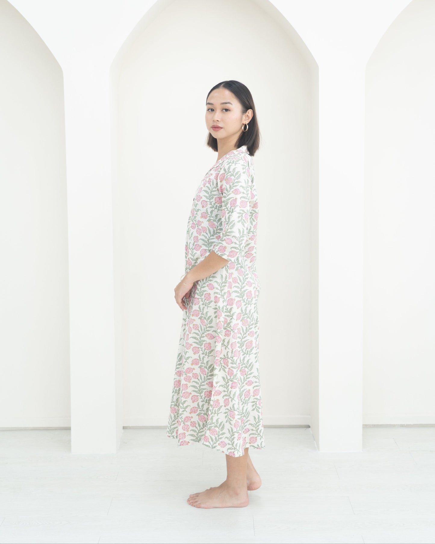 Woman wearing a floral dress standing against a white background