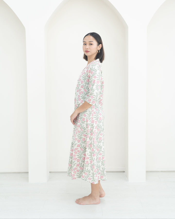 Woman wearing a floral dress standing against a white background