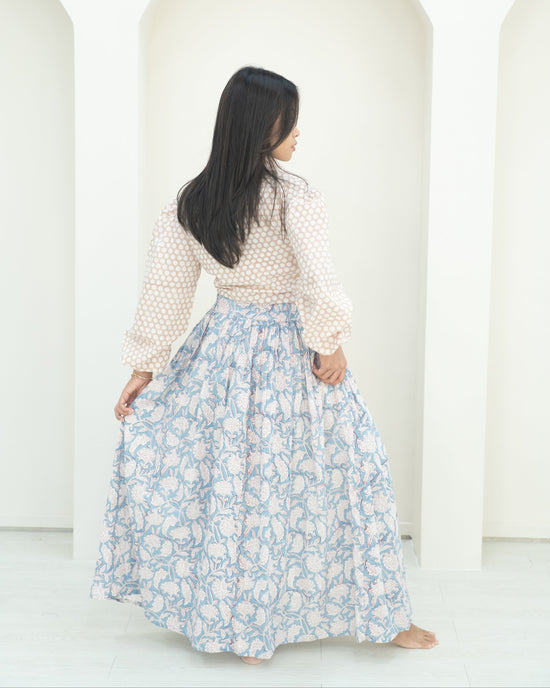 Woman wearing a white blouse with a blue floral skirt against a white background