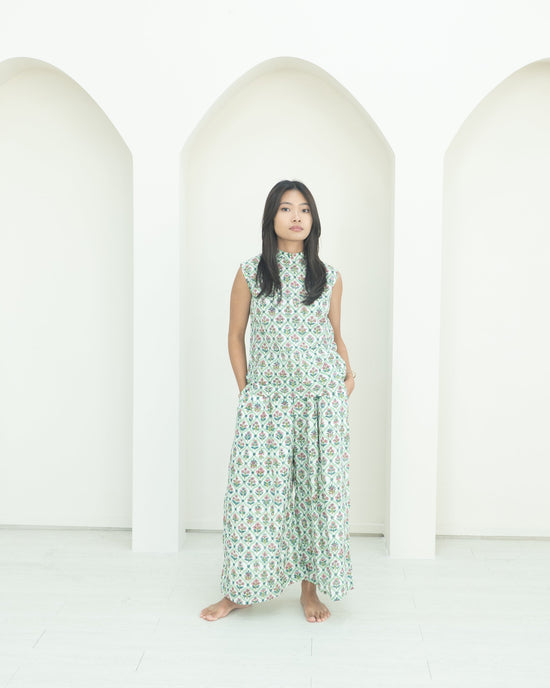 Woman wearing a green floral co-ord set standing in front of white arches.