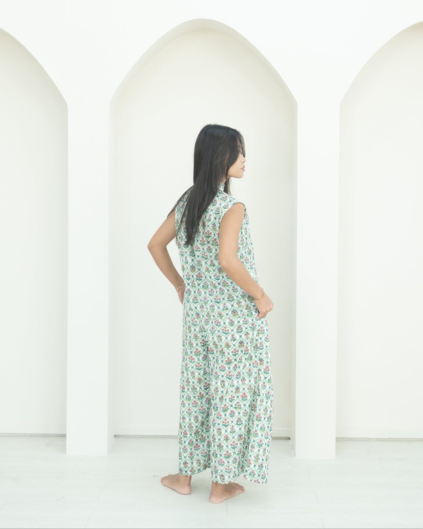 Woman wearing a green floral co-ord standing in front of white backdrop