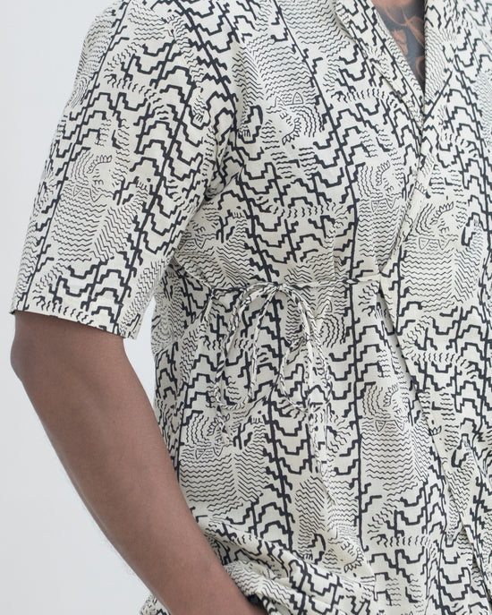 Person wearing a black and white patterned shirt on a plain background