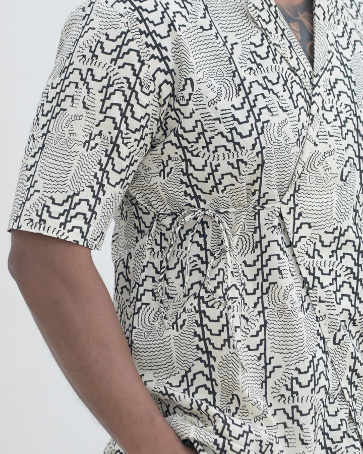 Person wearing a black and white patterned shirt on a plain background