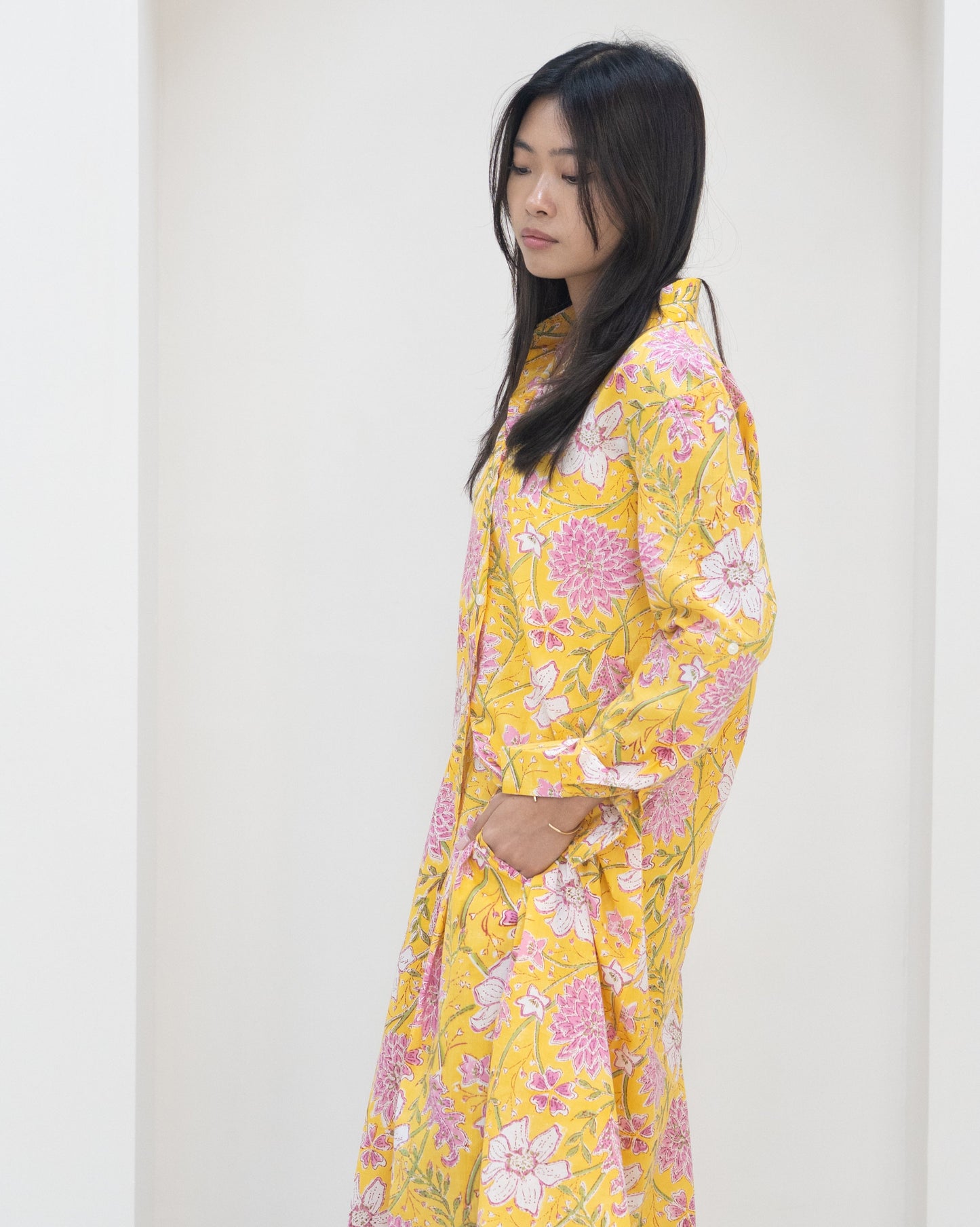 Woman wearing a yellow floral outfit against a white background