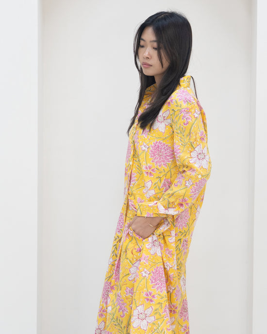 Woman wearing a yellow floral outfit against a white background