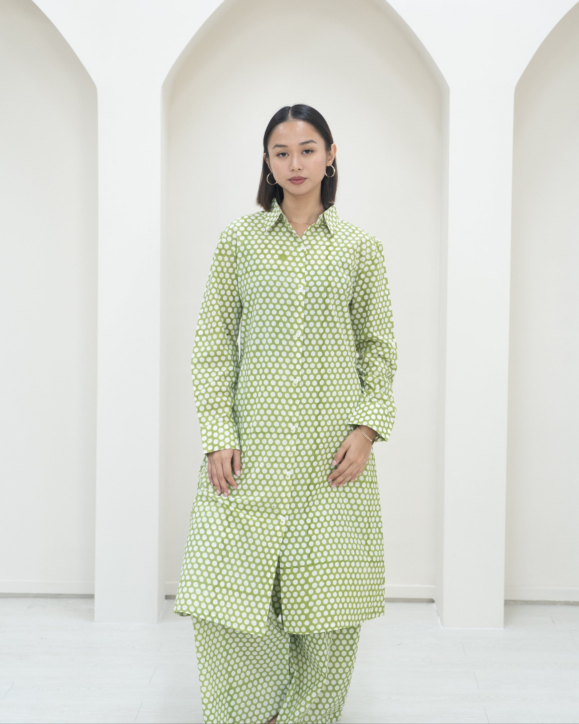 Woman wearing a green polka dot outfit against a white background