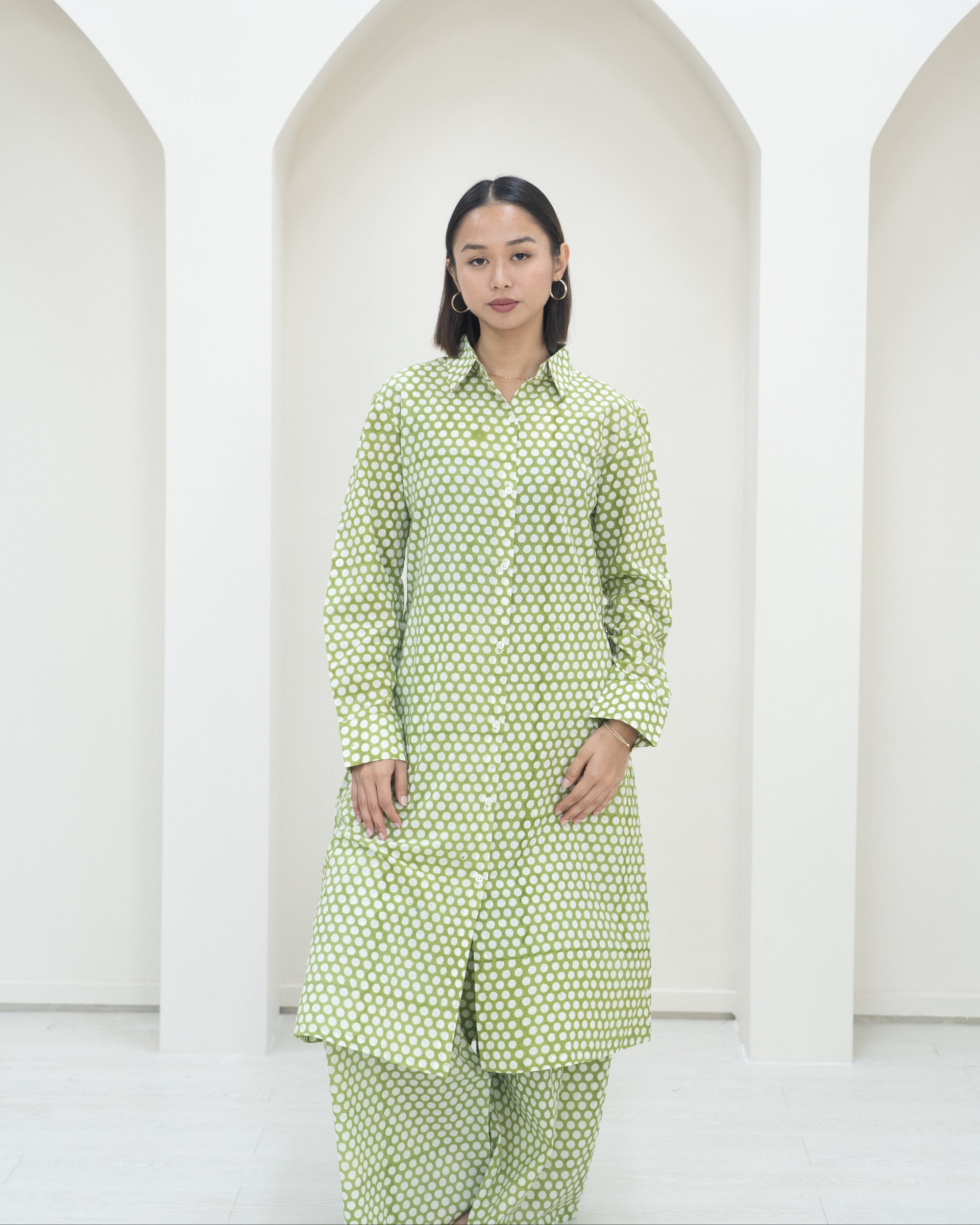 Woman wearing a green polka dot outfit against a white background