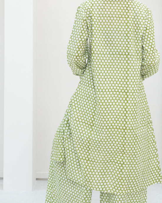 Person wearing a green polka dot dress against a white background