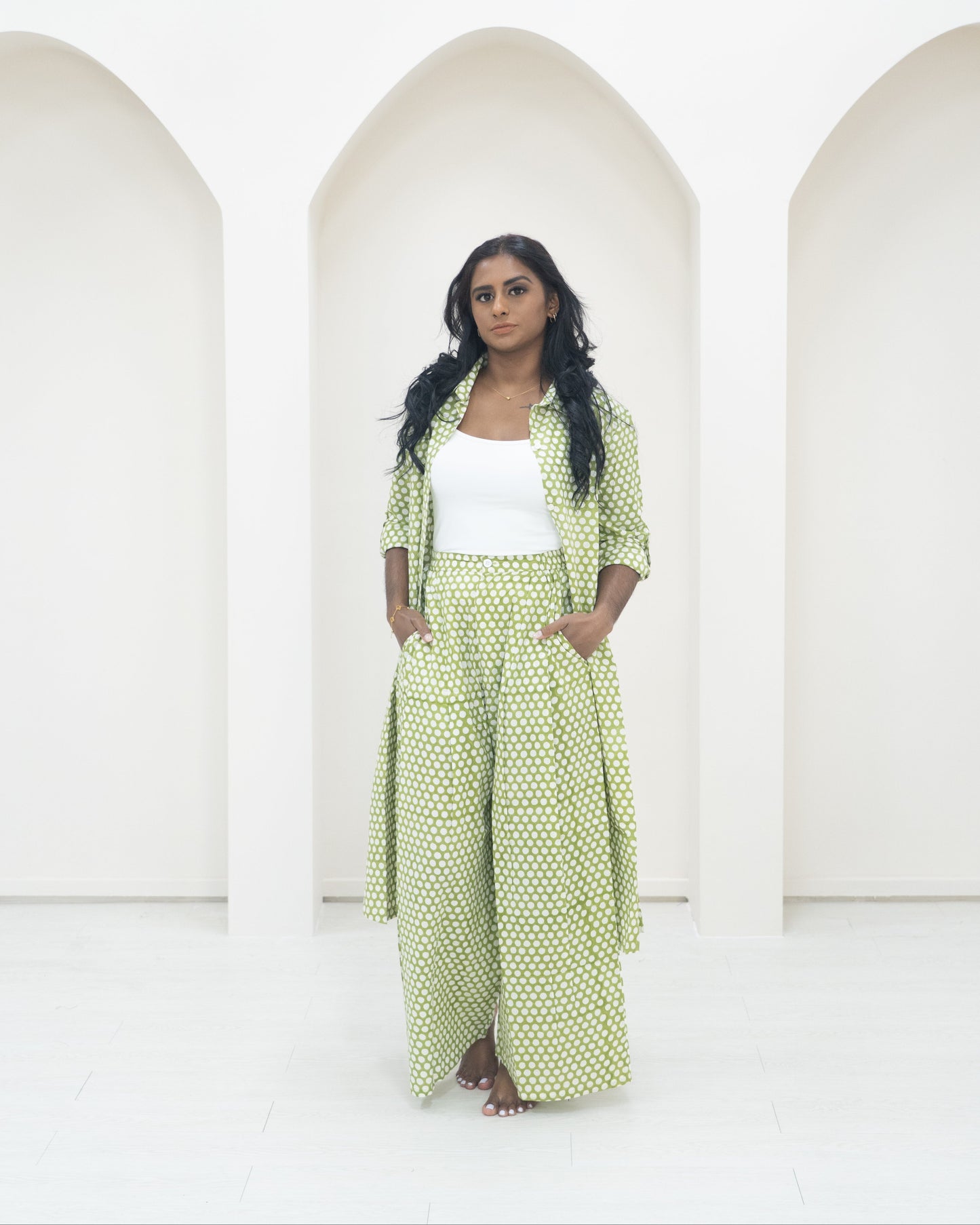 Woman in a green polka dot outfit standing in front of white background