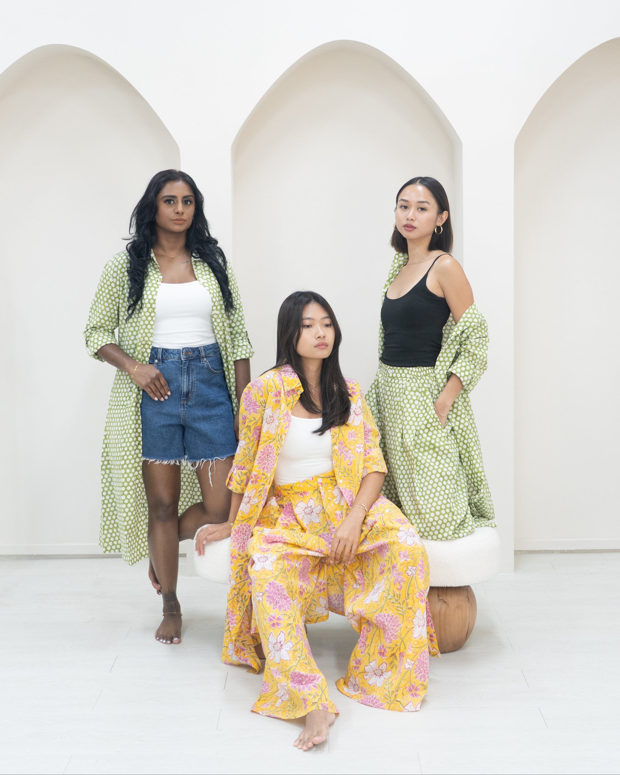 Three women in colorful outfits posing against a white background