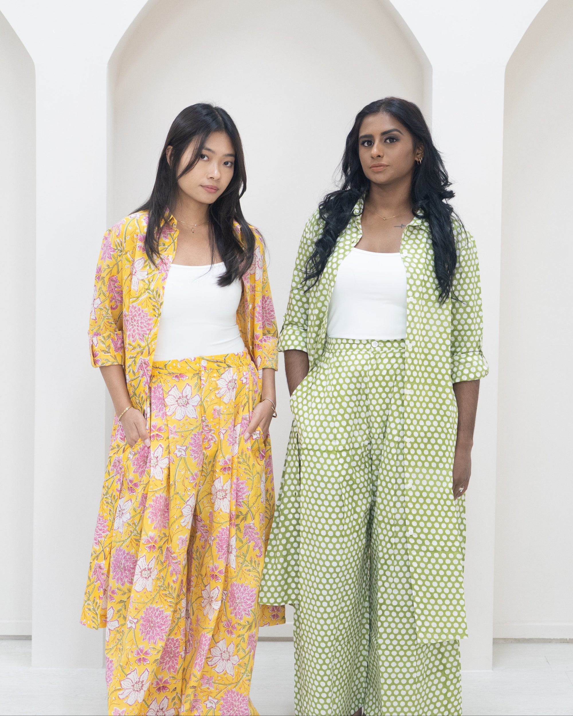 Two women wearing colorful outfits standing against a white background
