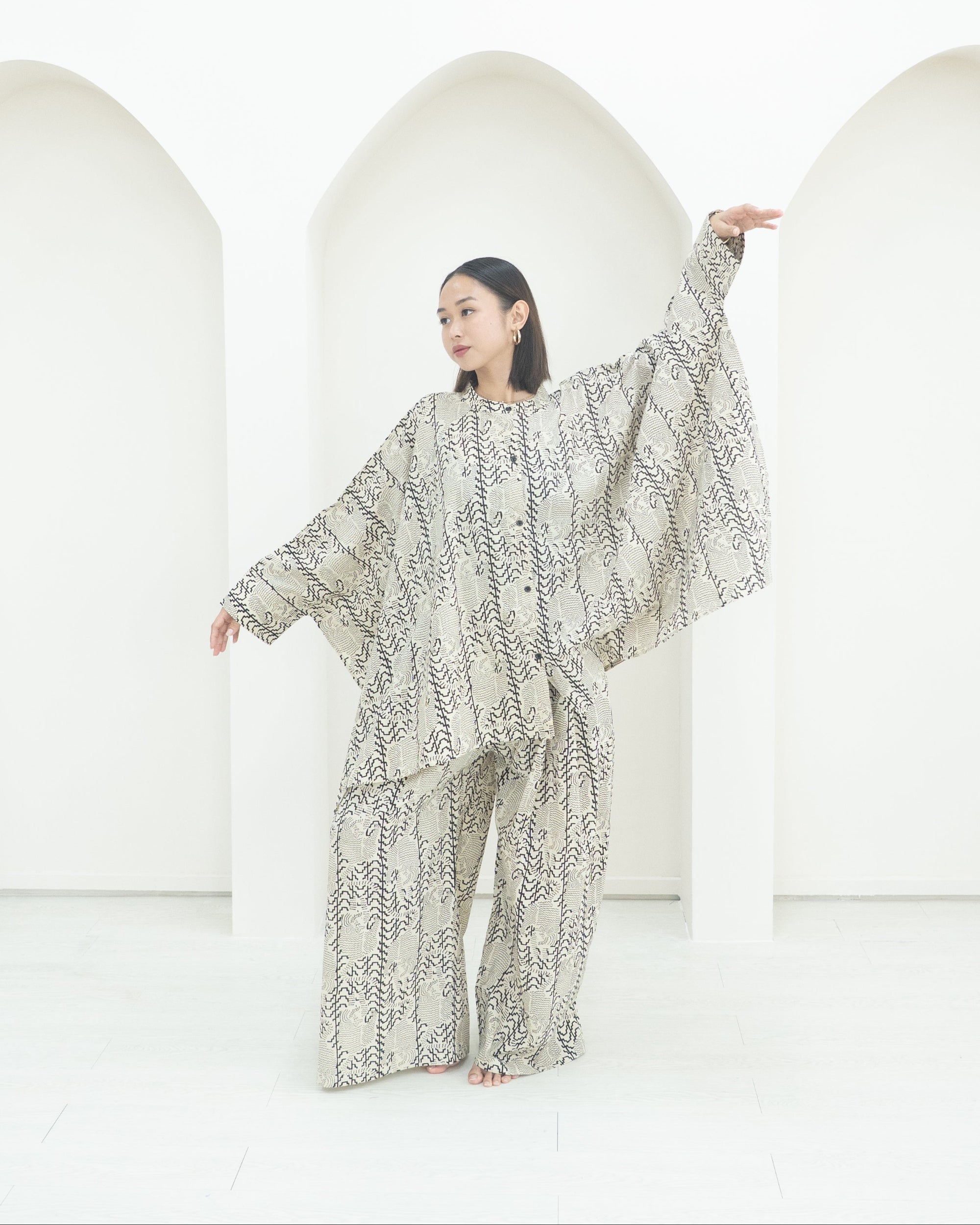 Person wearing a patterned outfit standing against a white background
