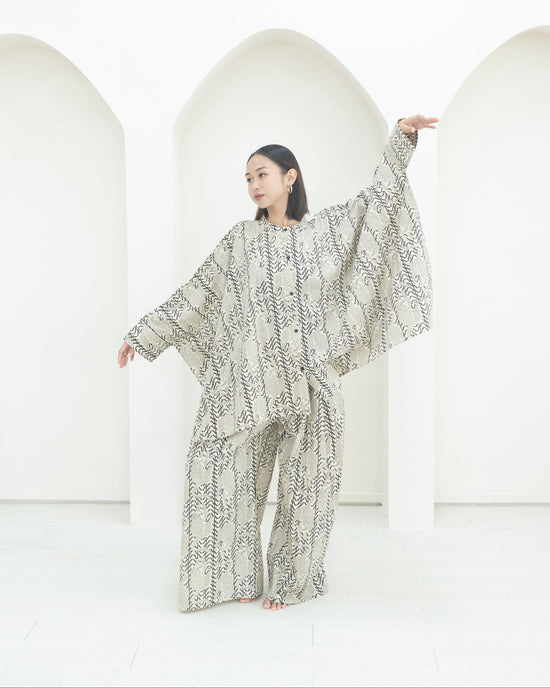 Person wearing a patterned outfit standing against a white background