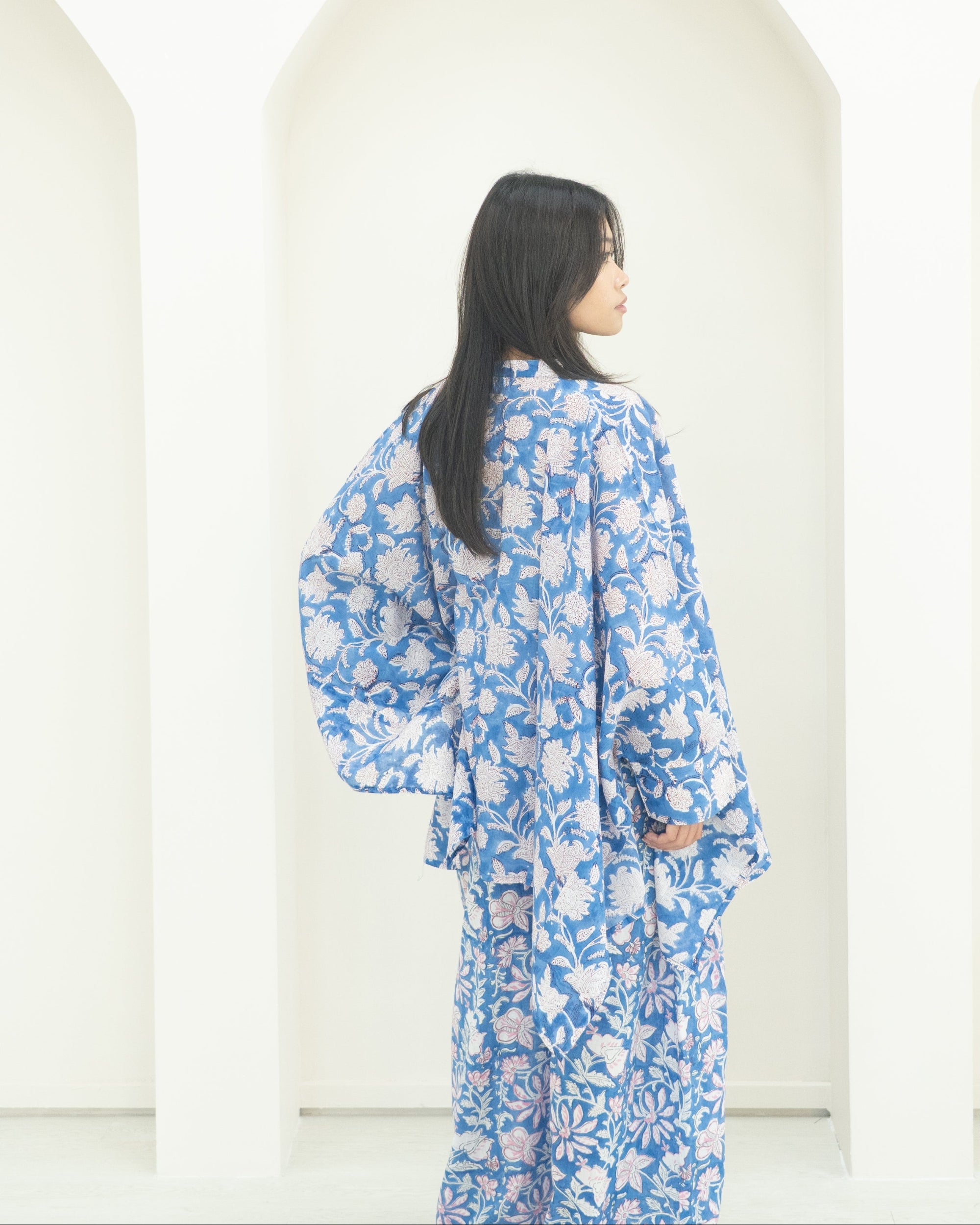 Woman wearing a blue floral kimono outfit standing against a white background