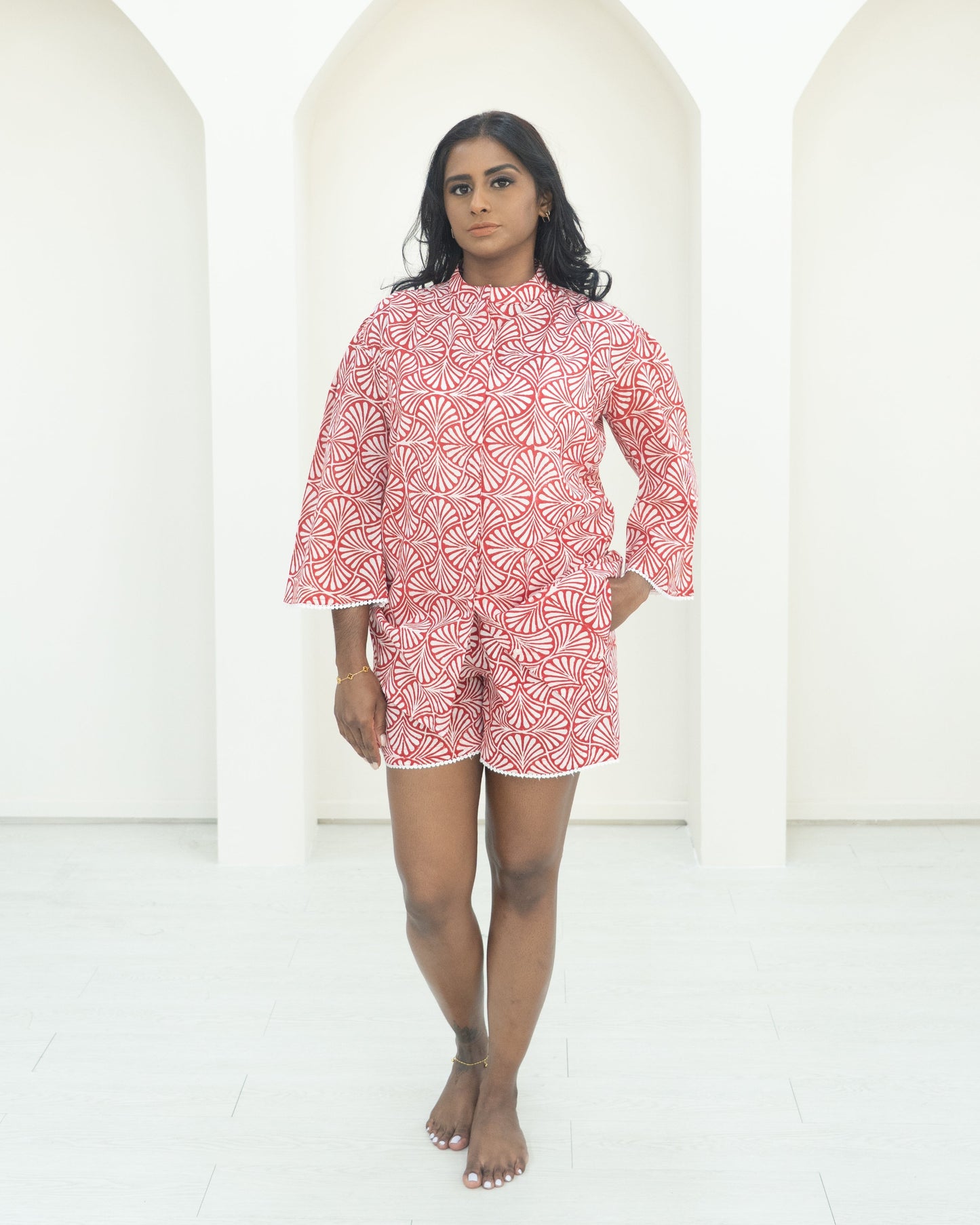 Woman wearing a red patterned dress standing against a white background