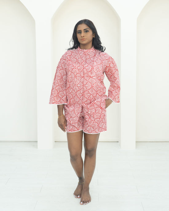 Woman wearing a red patterned dress standing against a white background