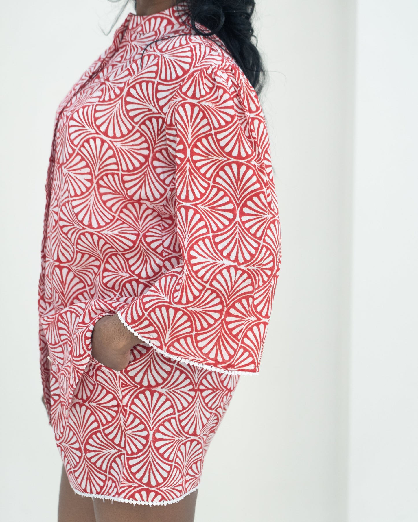 Person wearing a red and white patterned outfit against a white background