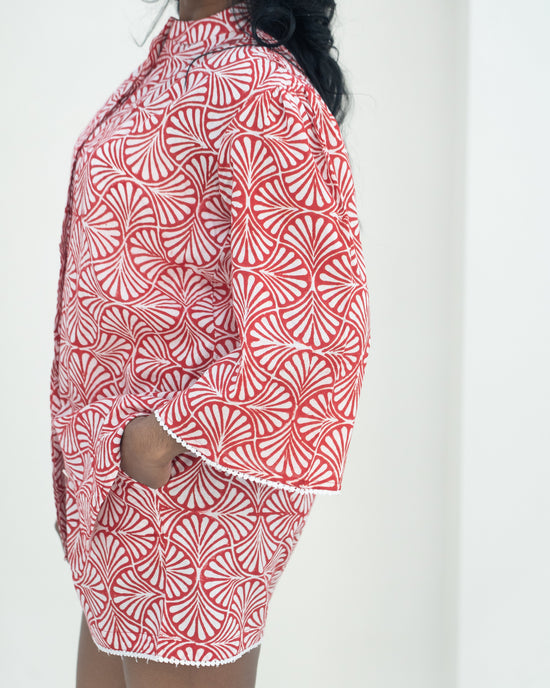 Person wearing a red and white patterned outfit against a white background