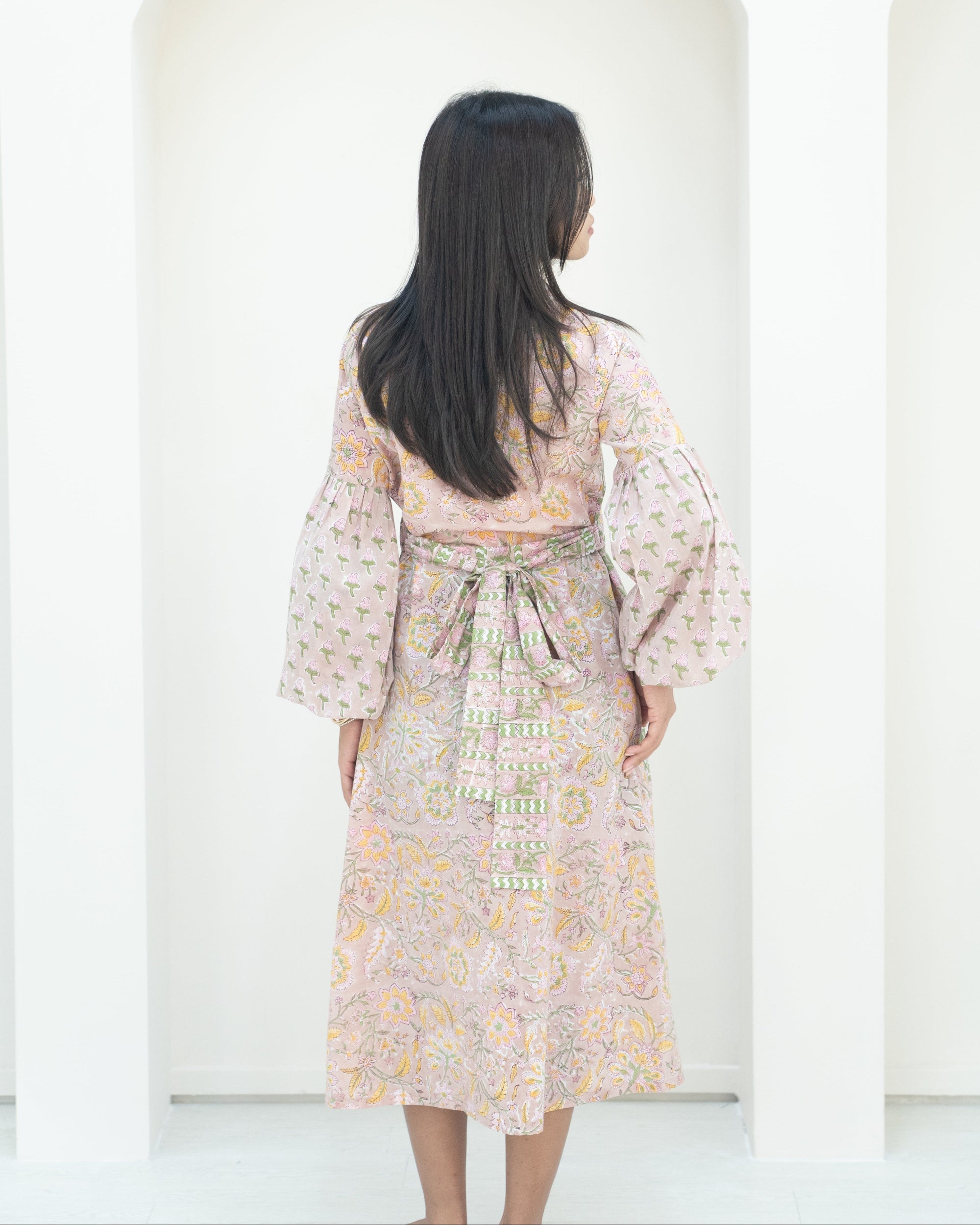 Woman wearing a floral dress with bell sleeves against a white background