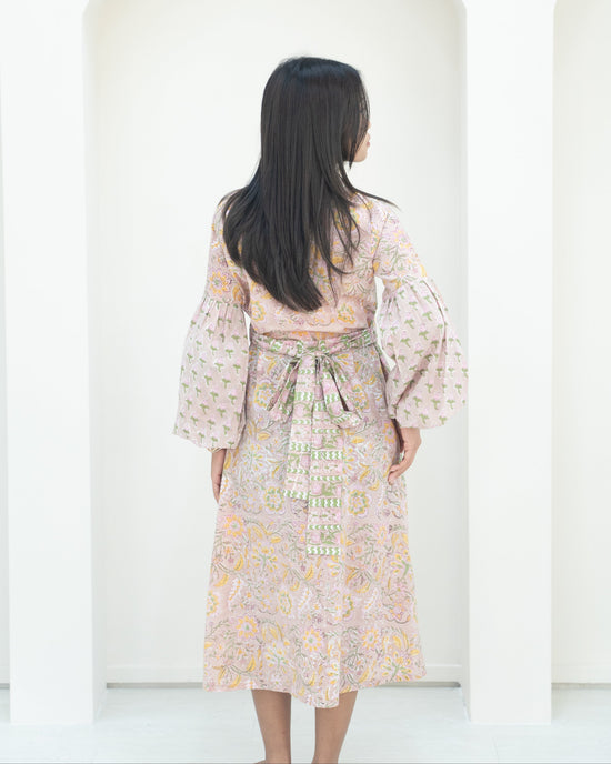Woman wearing a floral dress with bell sleeves against a white background