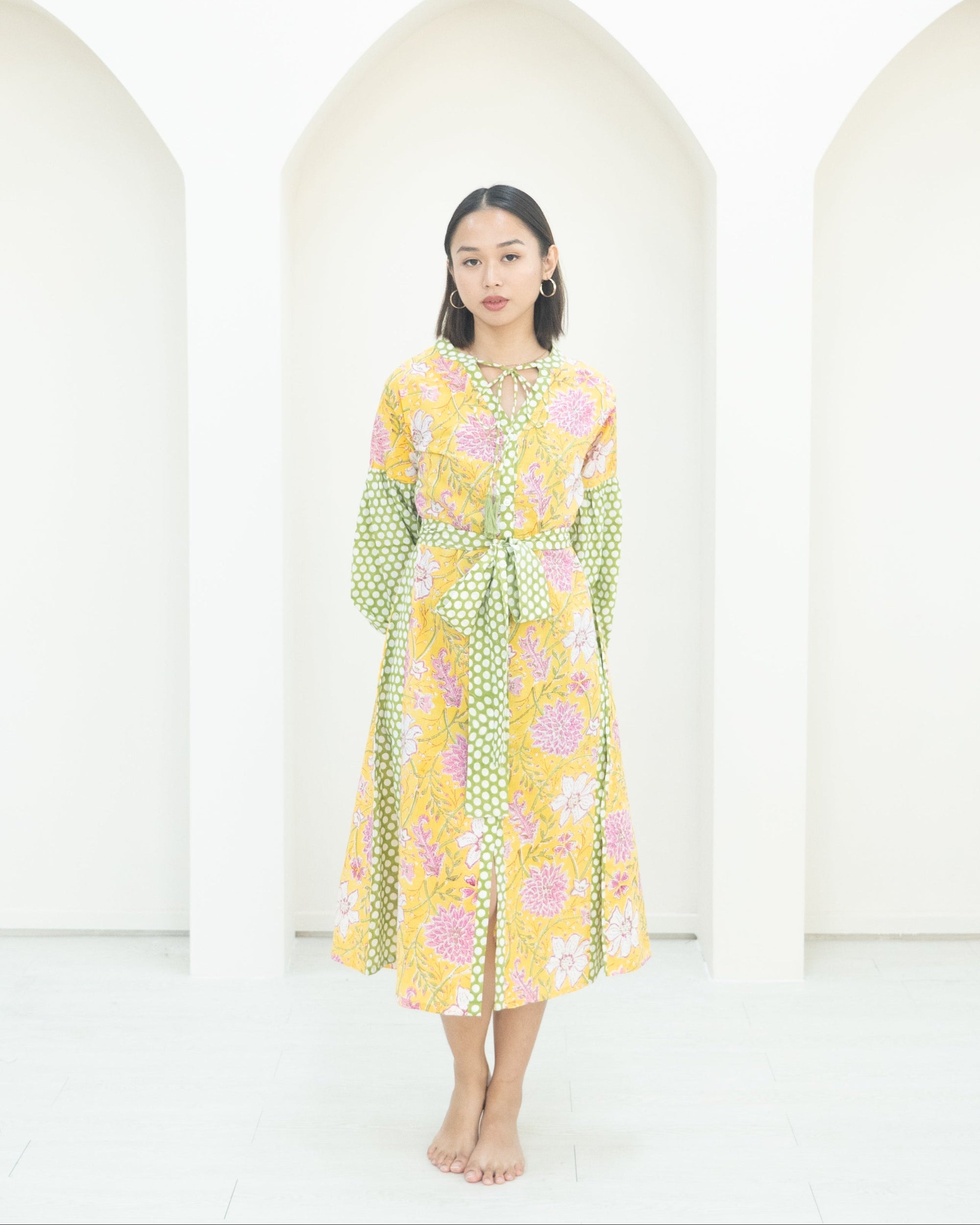 Woman wearing a floral dress standing against a white background