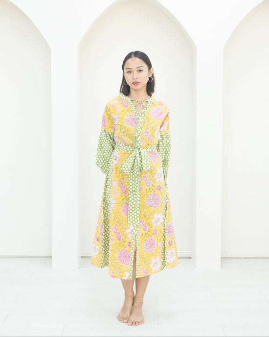 Woman wearing a floral dress standing against a white background