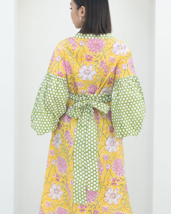 Woman wearing a colorful floral dress with polka dot sleeves on a white background