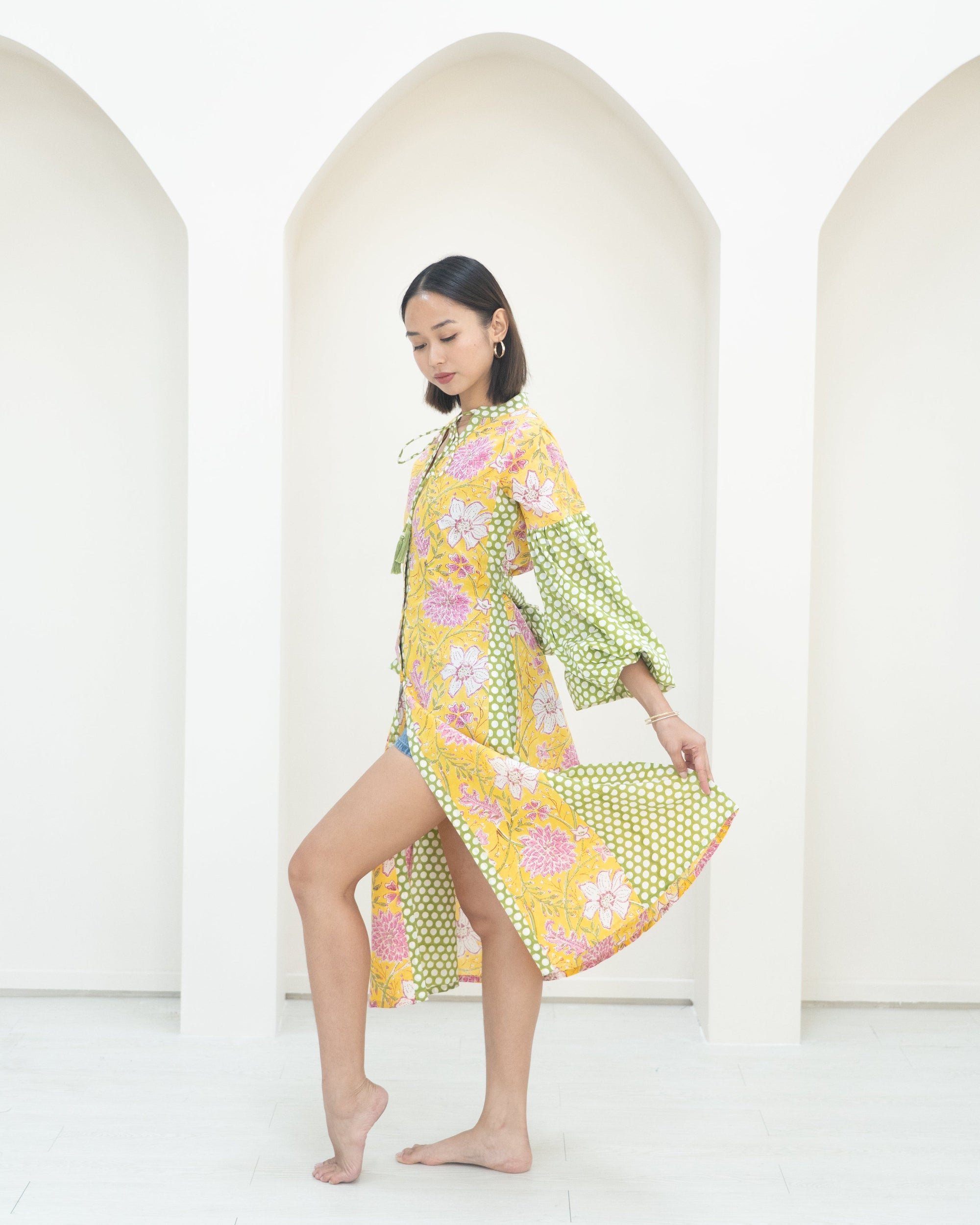 Woman wearing a colorful floral dress against a white background