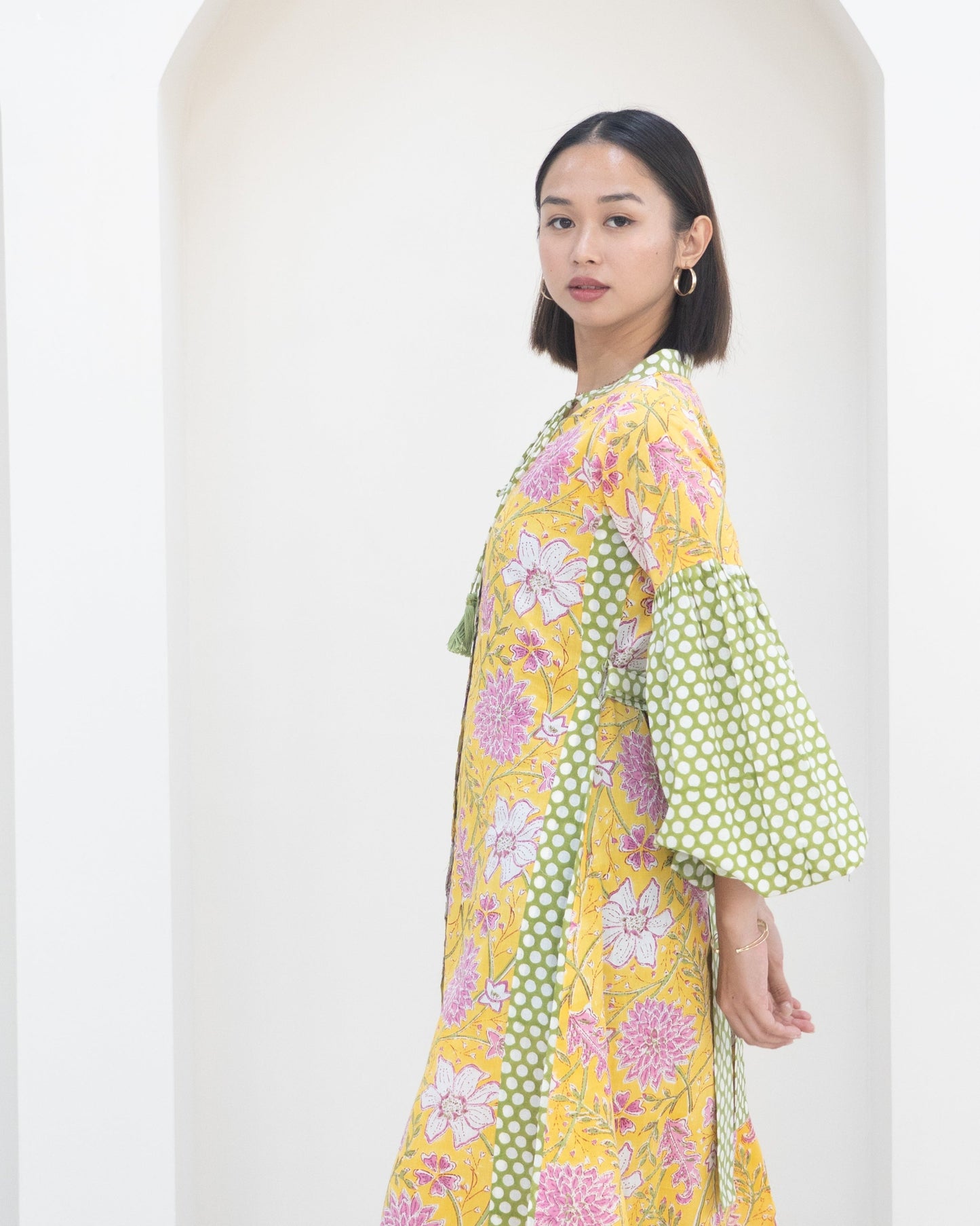 Woman wearing a colorful floral dress with bell sleeves against a white background