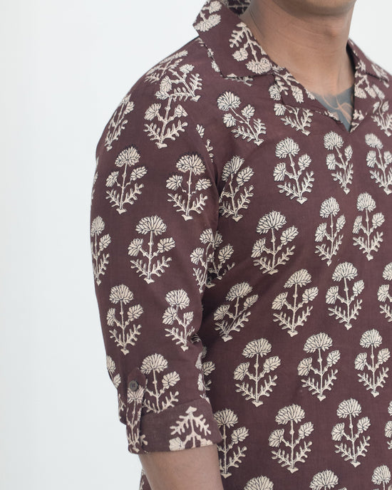 Man wearing a brown floral patterned shirt against a white background
