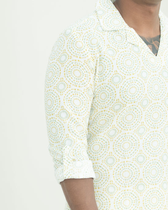 Person wearing a white patterned shirt on a plain background